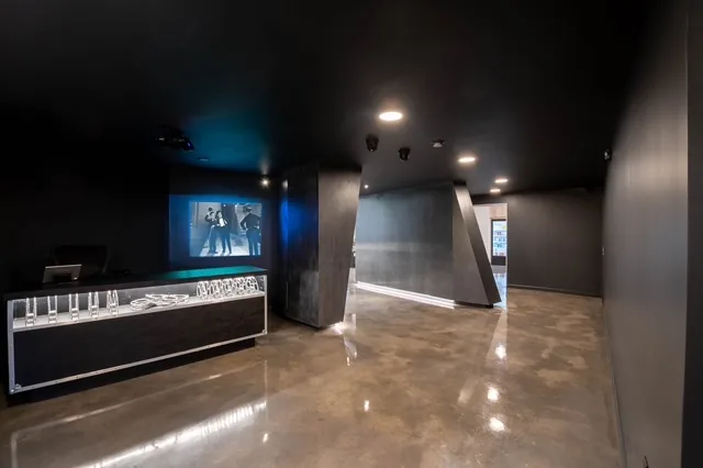 Dark interior entry with a screen, polished floor and angular passage toward the main room