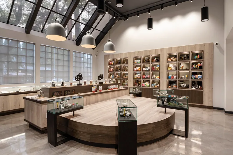 Pendant lights beneath a skylight above a round wood display and wall shelving